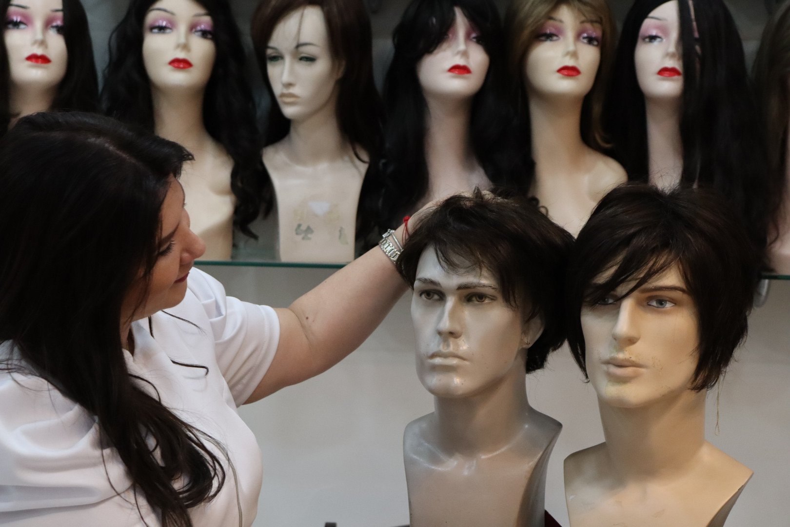 Cristina Orosa ajustando uma prótese capilar em manequim · expertise técnica de mais de 30 anos